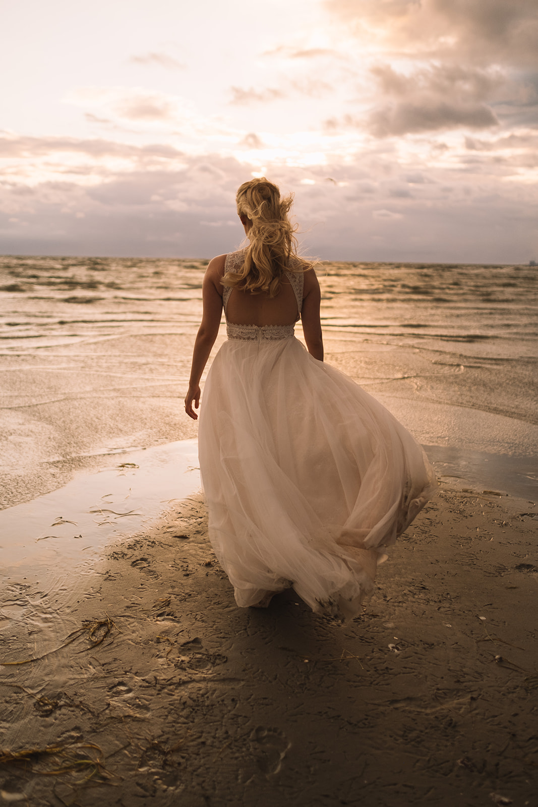 The bride wading into the sea in her wedding dress