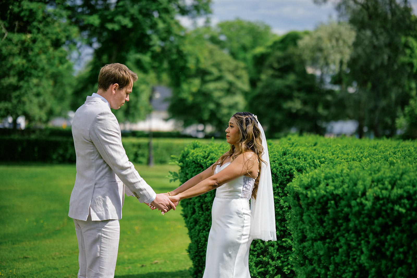 Bride and groom walking together beside the garden hedge