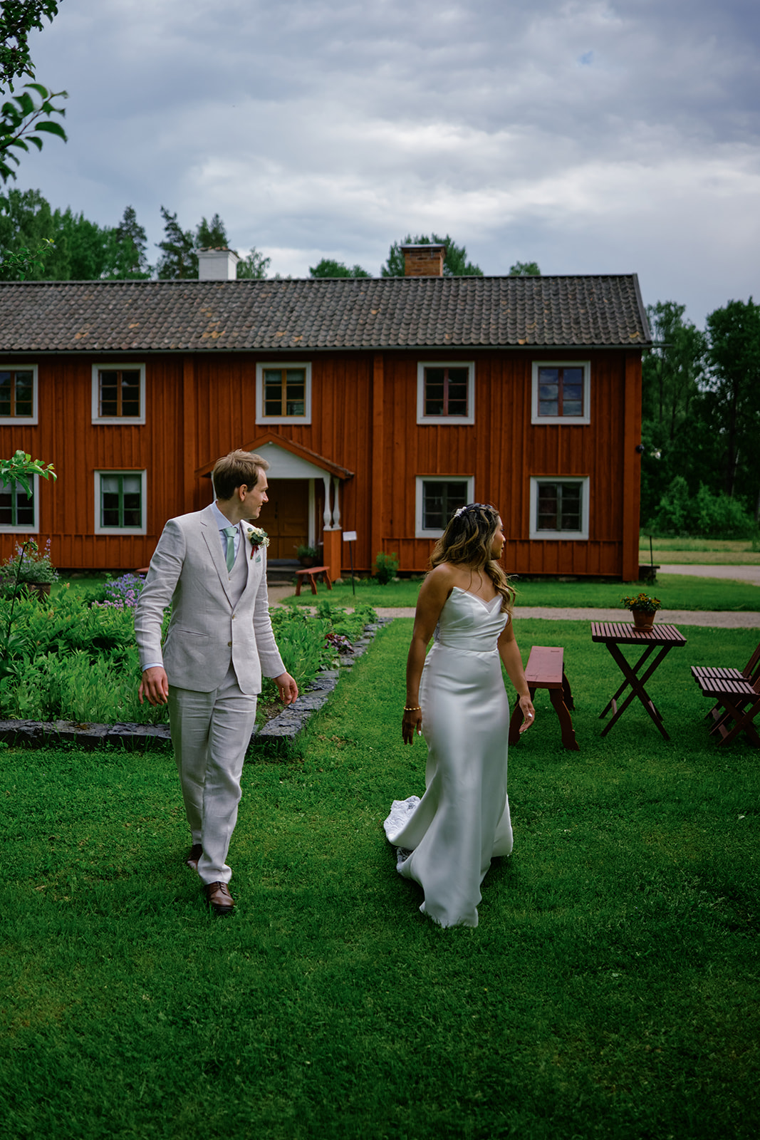 The couple walking between the red buildings of the ironworks village
