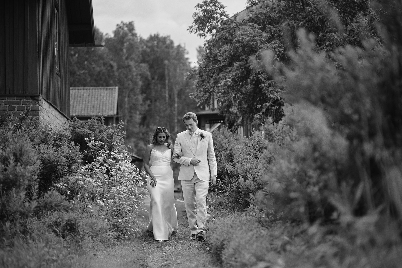 Pavi and Edvin walking a path through the trees, black and white