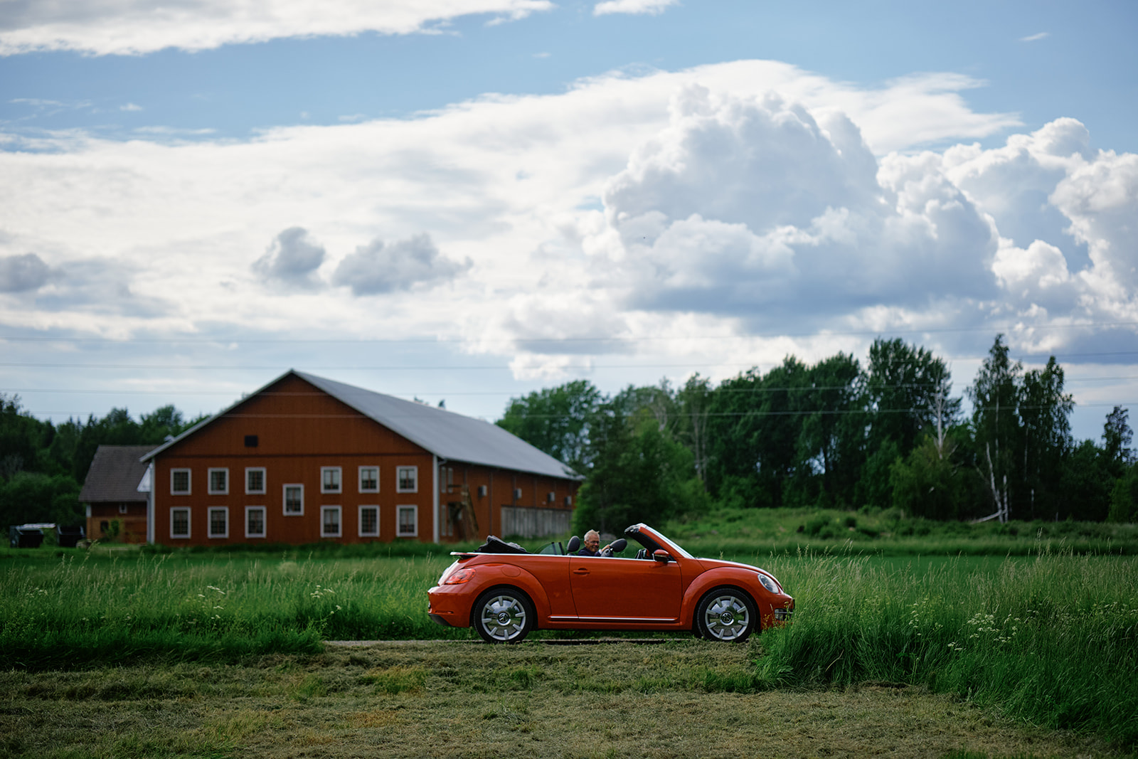 A red barn and a red car under a big sky at Gysinge