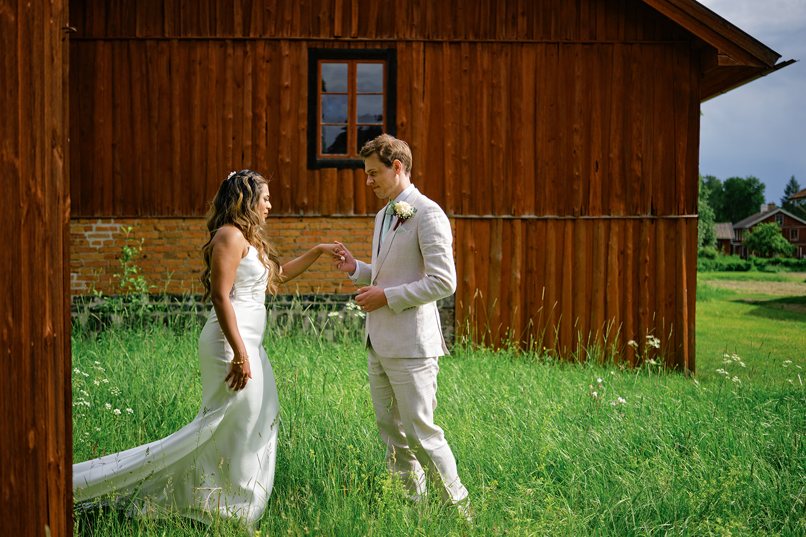 The couple laughing beside a falu red wall