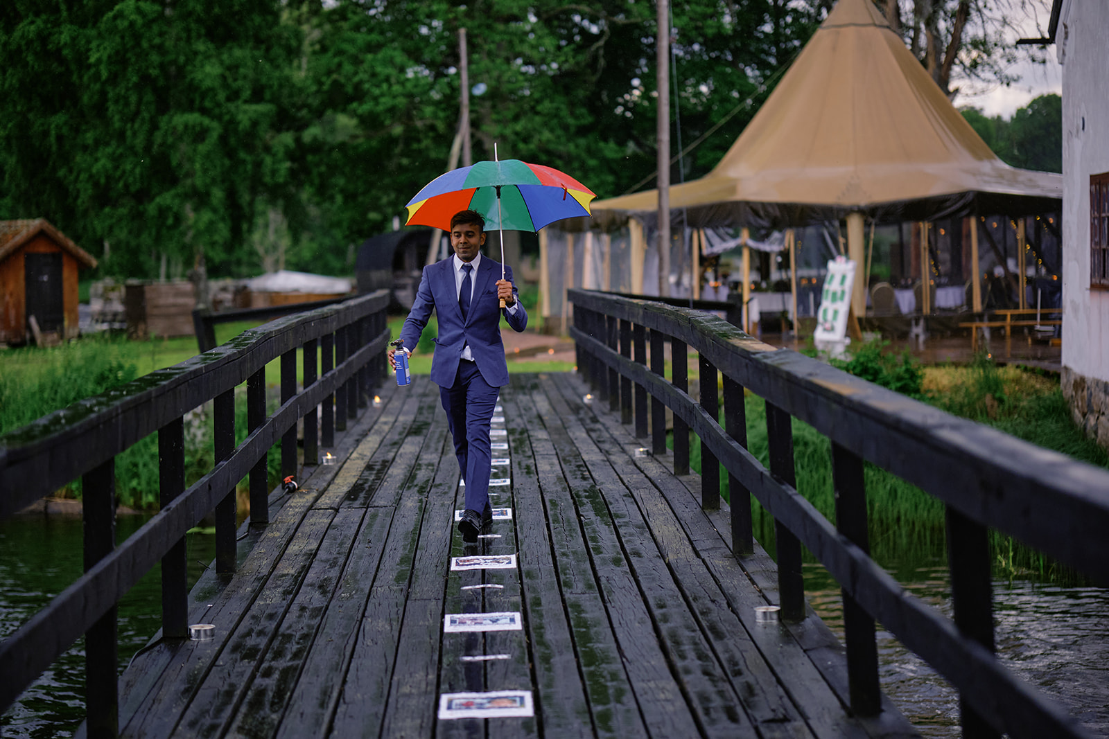 A guest crossing the covered bridge in the rain with an umbrella