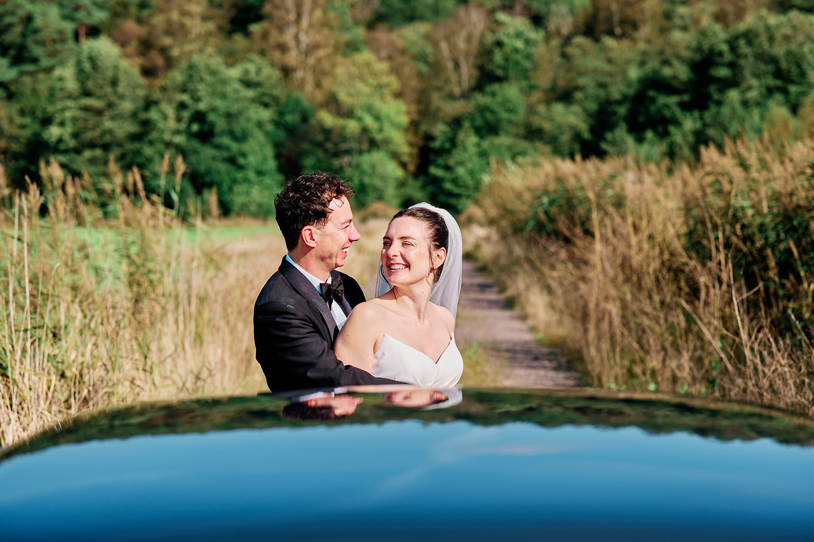 Bride and groom reflected in the roof of the wedding car