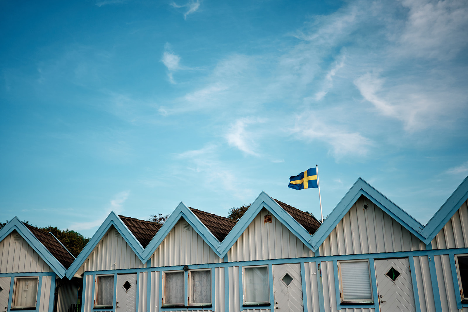 The blue bathing cabins and the Swedish flag against the sky