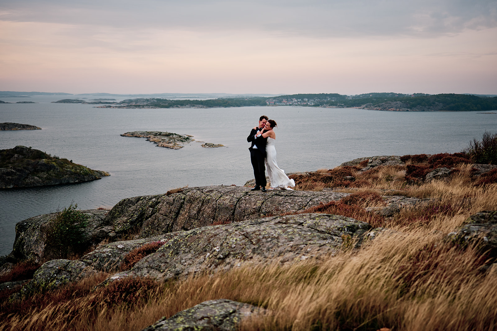 The couple small on the rocks above the water
