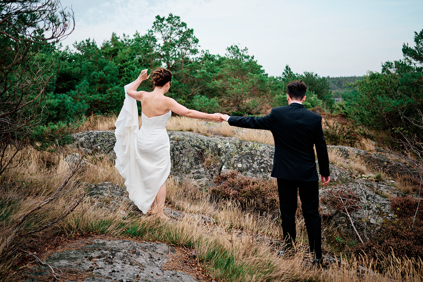 The bride pulling the groom across the grass, dress flying