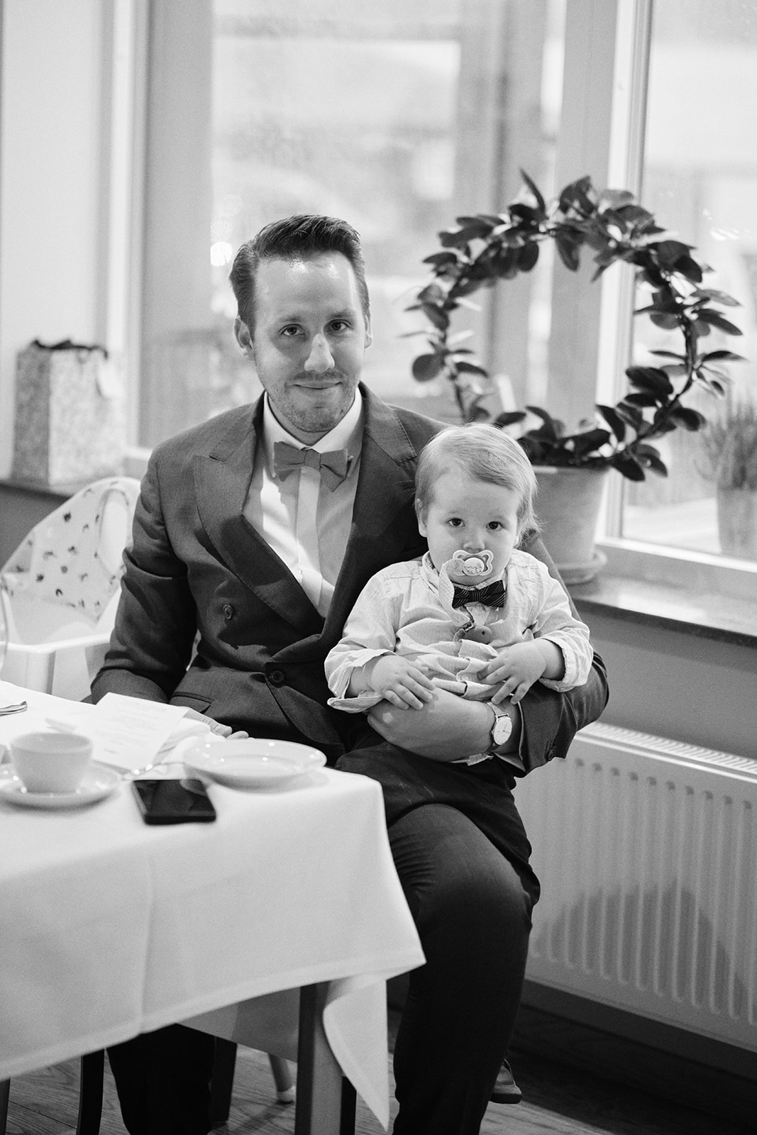 A guest holding a baby at the wedding dinner, black and white