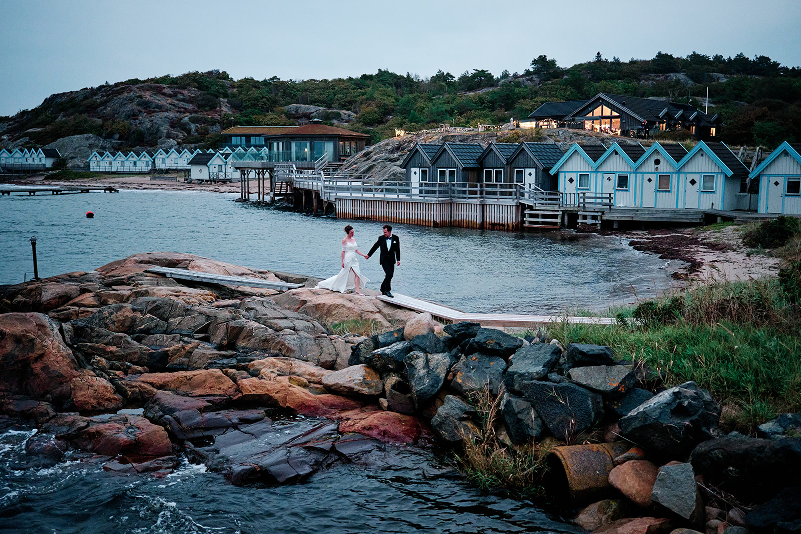 Bride and groom on the rocks with Hov&aring;s Kallbadhus behind them